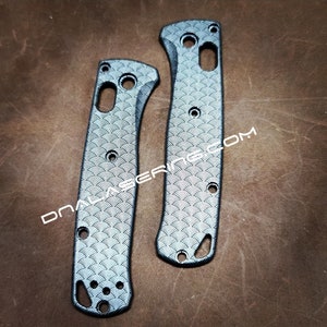 May include: Two gray knife handle scales with a wave pattern. The scales have multiple holes and a curved design. The text "DNALASER.COM" is printed on the scales.