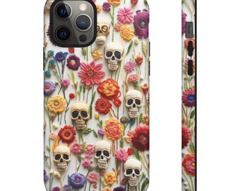 May include: A white phone case with a colorful floral pattern and embroidered skulls. The flowers are in shades of red, pink, yellow, orange, and purple. The skulls are white with black eye sockets.
