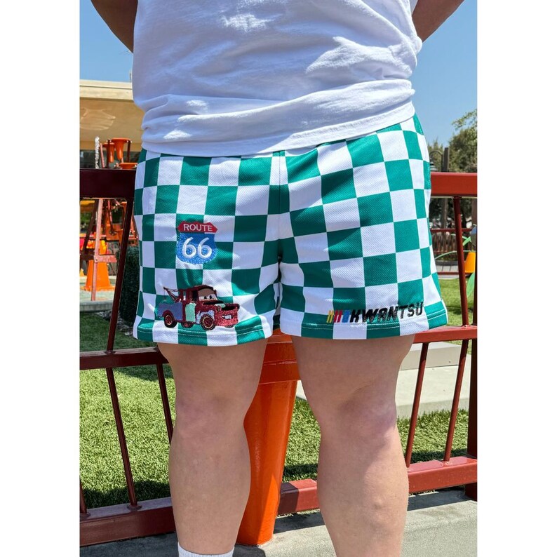May include: Green and white checkered shorts with a cartoon tow truck and "Route 66" sign on the left leg and "HWANTSU" text on the right leg.