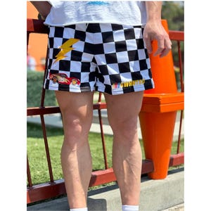May include: Black and white checkered shorts with a red race car and lightning bolt graphic. The shorts have the text "I WANT SO" on the side.