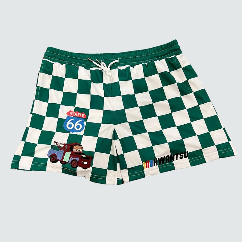 May include: Green and white checkered shorts with a cartoon tow truck and Route 66 sign. The shorts have the text "HWANTSU" on the bottom right side.