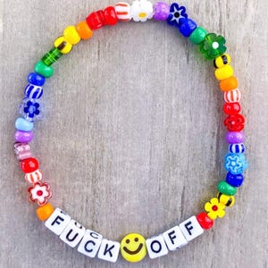 May include: A colorful beaded bracelet with a variety of beads in rainbow colors. The bracelet includes flower and smiley face beads, and the words "FUCK OFF" spelled out in white letter beads.
