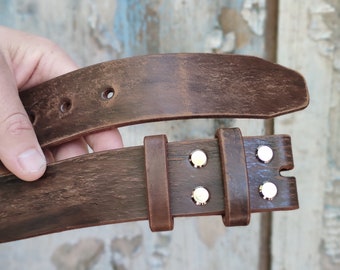 May include: A brown leather belt with a silver buckle and four silver rivets. The belt is folded in half, showing the buckle and rivets.
