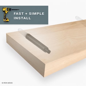 Puede incluir: Un estante flotante de madera clara con dos soportes de montaje metálicos integrados. Un gráfico en la esquina muestra un taladro amarillo y negro con el texto FAST + SIMPLE INSTALL. El nombre de la marca IRON ABODE aparece en la parte inferior.