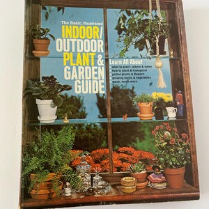 May include: A vintage wooden display case with glass shelves, filled with potted plants and decorative items. The case features a book titled "Indoor/Outdoor Plant & Garden Guide". The background shows a vibrant outdoor scene.
