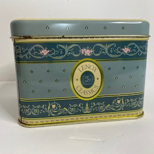 May include: A blue and gold tin box with a floral design and the text "LENOX CLASSICS" in a circle.