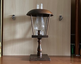 May include: A wooden lamp with a glass shade and a dark brown finish. The lamp has a round base and a cylindrical stem.