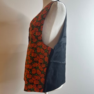 May include: A black sleeveless vest with a pumpkin print on the front. The vest is made of a soft, silky fabric and has a simple, classic design.