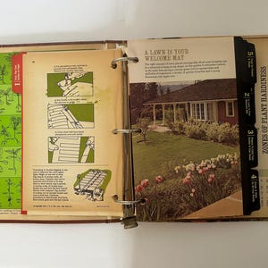 May include: Open vintage gardening book with illustrations and text. The left page shows plant identification, while the right page features a house with a lawn and the text "A Lawn Is Your Welcome Mat."
