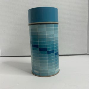 May include: A blue and white thermos with a geometric pattern. The thermos has the word "THERMOS" printed on the bottom.