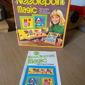 May include: A vintage Mattel Needlepoint Magic craft kit with a colorful box featuring a girl and a needlepoint loom. The box includes instructions for making needlepoint projects, including a pillow with a cat and dog design.