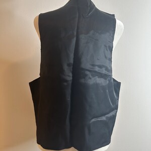 May include: A black sleeveless vest with a smooth, satin-like finish. The vest is displayed on a white mannequin.