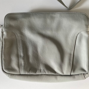 May include: A gray leather shoulder bag with a flap closure and a single strap.
