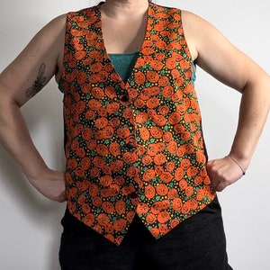May include: A black vest with a pumpkin pattern. The vest has a button closure and is made of a soft, comfortable fabric.