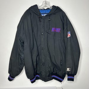 May include: Black hooded jacket with the word "GIANTS" in purple and blue lettering. The jacket has a snap closure, blue and red striped cuffs, and the NFL logo. The Starter brand logo is visible on the sleeve.