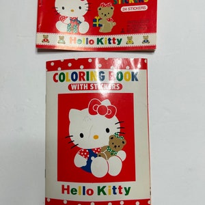 May include: A red and white coloring book with Hello Kitty and a bear on the cover. The book has a title that reads "Coloring Book with Stickers".