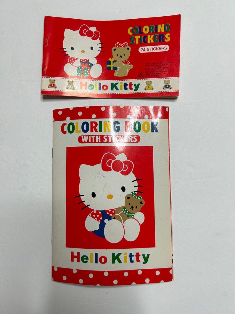 May include: A red and white coloring book with Hello Kitty and a bear on the cover. The book has a title that reads "Coloring Book with Stickers".
