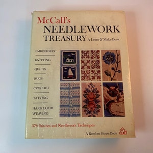 May include: A vintage book titled "McCall's Needlework Treasury: A Learn & Make Book" with a yellow cover and colorful illustrations of various needlework projects, including embroidery, knitting, quilts, rugs, crochet, tatting, hand loom, and weaving. The book states it contains 879 stitches and needlework techniques and is a Random House book.