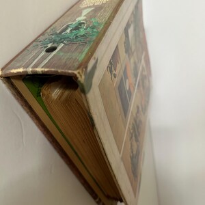 May include: Vintage hardcover book with a worn, rustic appearance. The spine features text and a decorative illustration of a figure in a forest setting. The book's pages are aged, and the cover displays a collage of images.
