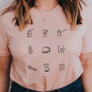 May include: A pink t-shirt with a graphic of various coffee brewing methods, including a French press, a pour-over, and a percolator. The text "ADULT UNISEX", "Quality Fabric", "Premium Design", "Made to Order", "Responsive Team", and "HEATHER PEACH" is printed on the bottom of the image.