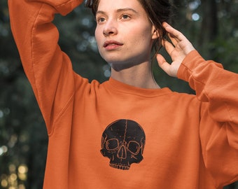 May include: A bright orange sweatshirt with a black skull graphic on the front. The sweatshirt is made of a soft, comfortable material and has a relaxed fit.