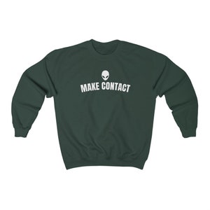 May include: A dark green sweatshirt with a white alien head graphic and the text "MAKE CONTACT" printed on the front.