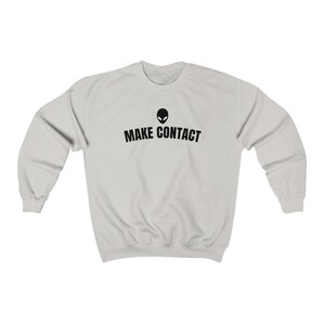 May include: A light gray sweatshirt with a black alien head graphic and the text "MAKE CONTACT" printed on the front.