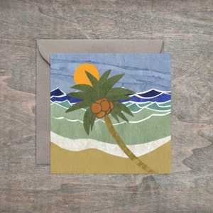 Könnte beinhalten: Eine bunte Papiercollage-Karte mit einer Palme mit Kokosnüssen an einem Strand mit blauen Wellen und einer gelben Sonne.