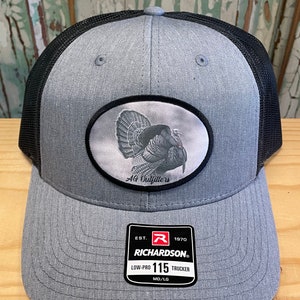 May include: A gray and black trucker hat with a patch featuring a turkey and the text "AG Outfitters". The hat also has a red and white label with the text "EST. 1970 RICHARDSON. LOW-PRO 115 TRUCKER MD/LG".