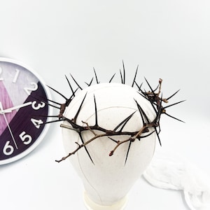 Op de afbeelding: Een doornenkroon gemaakt van gedroogde takken met scherpe zwarte doornen. De kroon is geplaatst op een wit mannequin hoofd.