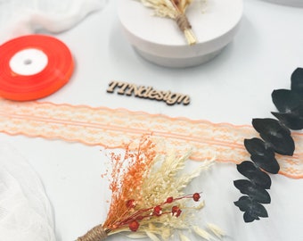 Puede incluir: Primer plano de un pequeño ramo de flores secas con tonos naranja y crema, atado con hilo. La imagen también muestra un rollo de cinta naranja, encaje naranja y un letrero de madera que dice "TTNdesign".