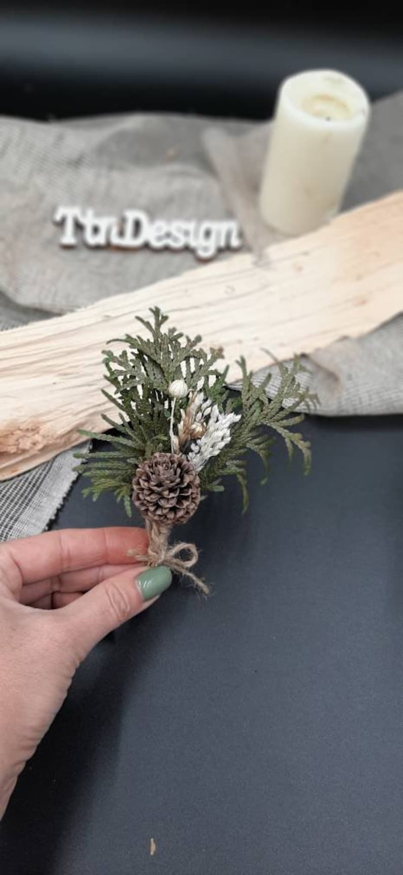 May include: A small bouquet of dried greenery and pine cones tied with twine. The bouquet is brown, green, and white.