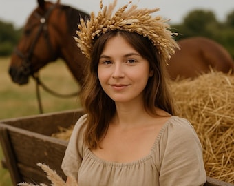 May include: A woman wearing a wheat crown and a beige dress, posing outdoors. A brown horse and a wooden cart are in the background. The woman is holding a bundle of wheat.
