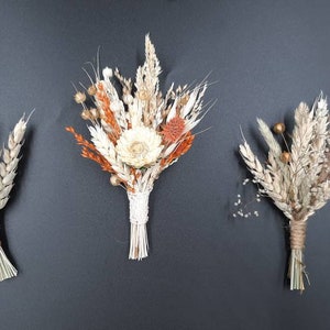 May include: Three dried flower bouquets with a rustic, natural aesthetic. The bouquets are made with dried grasses, wheat, and small white and orange flowers.