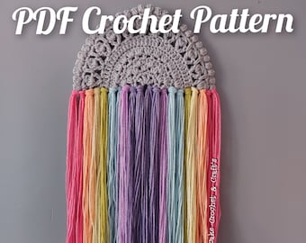 May include: A crochet rainbow wall hanging with a gray crocheted top and colorful yarn tassels. The image includes the text "PDF Crochet Pattern Instant Download".