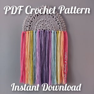 Könnte beinhalten: Ein gehäkeltes Regenbogen-Wandbehang mit einer grauen gehäkelten Oberseite und bunten Garnquasten. Das Bild enthält den Text "PDF Crochet Pattern Instant Download".