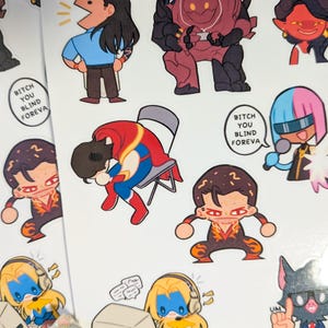 Puede incluir: Una hoja de pegatinas coloridas con personajes de dibujos animados en varias poses. Una pegatina tiene el texto "Bitch You Blind Foreva". Otras pegatinas incluyen un personaje con auriculares y un ordenador.