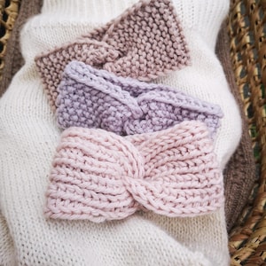 Peut inclure: Plusieurs bandeaux tricotés dans des tons pastel doux, notamment rose, lavande et taupe. Les bandeaux sont disposés sur un pull en tricot blanc, mettant en valeur leur texture et leur design. Ces bandeaux sont un accessoire de mode.