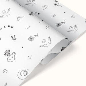 May include: White wrapping paper with a repeating pattern of black line drawings. The pattern includes flowers, moons, stars, mountains, and hands.