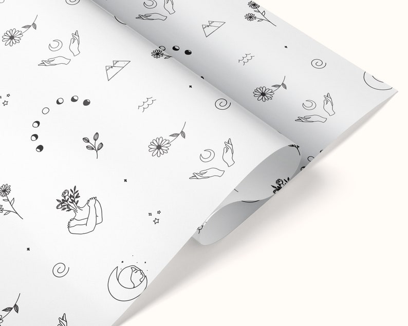 May include: White wrapping paper with a repeating pattern of black line drawings. The pattern includes flowers, moons, stars, mountains, and hands.