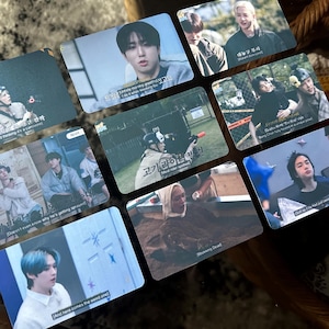 May include: A collection of nine rectangular photo cards featuring images of people in various settings. Some cards have text in Korean and English. The cards are arranged on a textured surface, with a warm color palette.