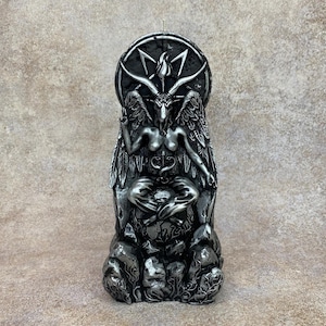 May include: A black and silver candle sculpture of a figure sitting on a throne with a pentagram behind them. The figure has horns, wings, and a crown.