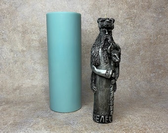 Puede incluir: Una vela plateada con un diseño detallado de un hombre barbudo sosteniendo un lobo. La vela está sobre un fondo azul claro. La vela dice "BELEC" en la parte inferior.