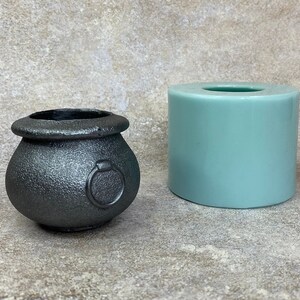May include: A black cauldron-shaped silicone mould with a ring handle and a teal-coloured silicone mould for making candles.