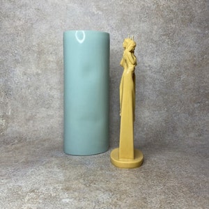 Pu&ograve; includere: Una scultura in resina gialla di due figure in piedi una accanto all'altra. Le figure indossano lunghe vesti e si abbracciano. La scultura &egrave; su una base rotonda.