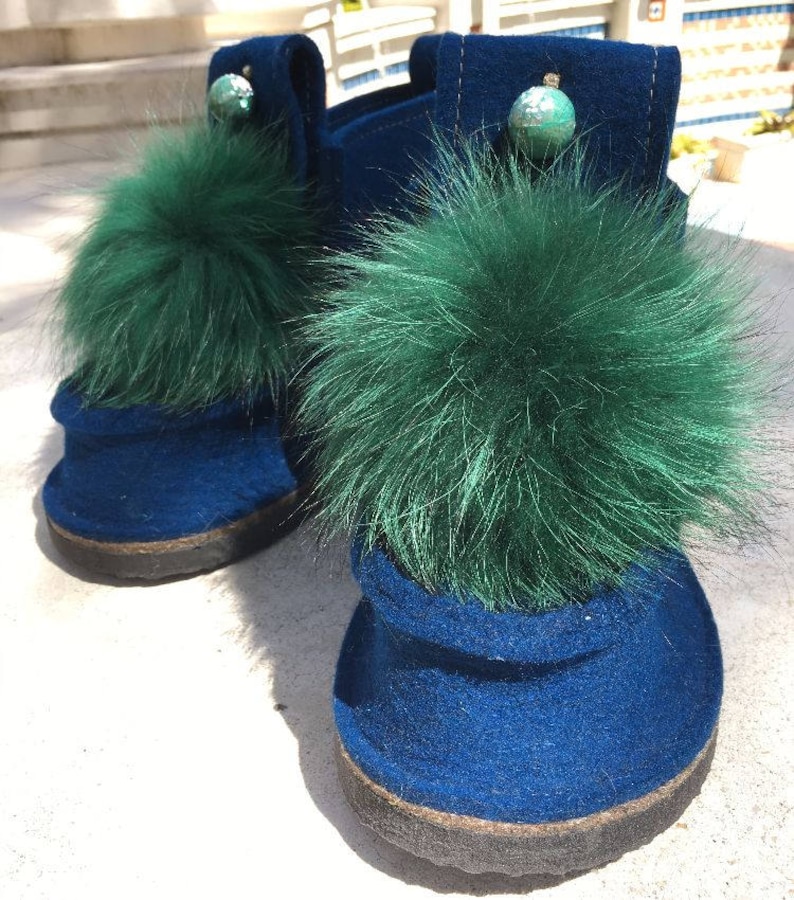 May include: Pair of blue felt boots with green fur pom-poms and decorative accents.