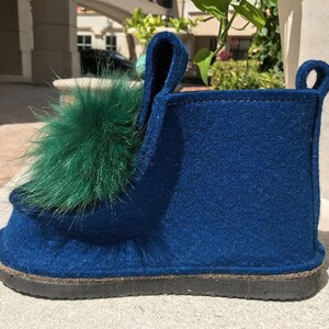 May include: Blue felt slipper with a green fur pom-pom on the top.