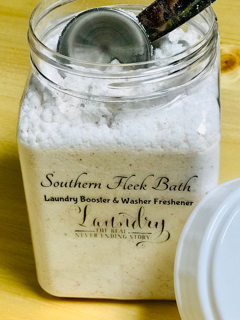 May include: A clear glass jar filled with white laundry booster powder. The jar has a black label that reads "Southern Fleek Bath Laundry Booster & Washer Freshener Laundry The Real Never Ending Story".