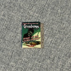 May include: A paperback book titled "Night of the Living Dummy" from the Goosebumps series. The cover features a green background with a menacing ventriloquist dummy and the Goosebumps logo. The author's name, R.L. Stine, is also visible.