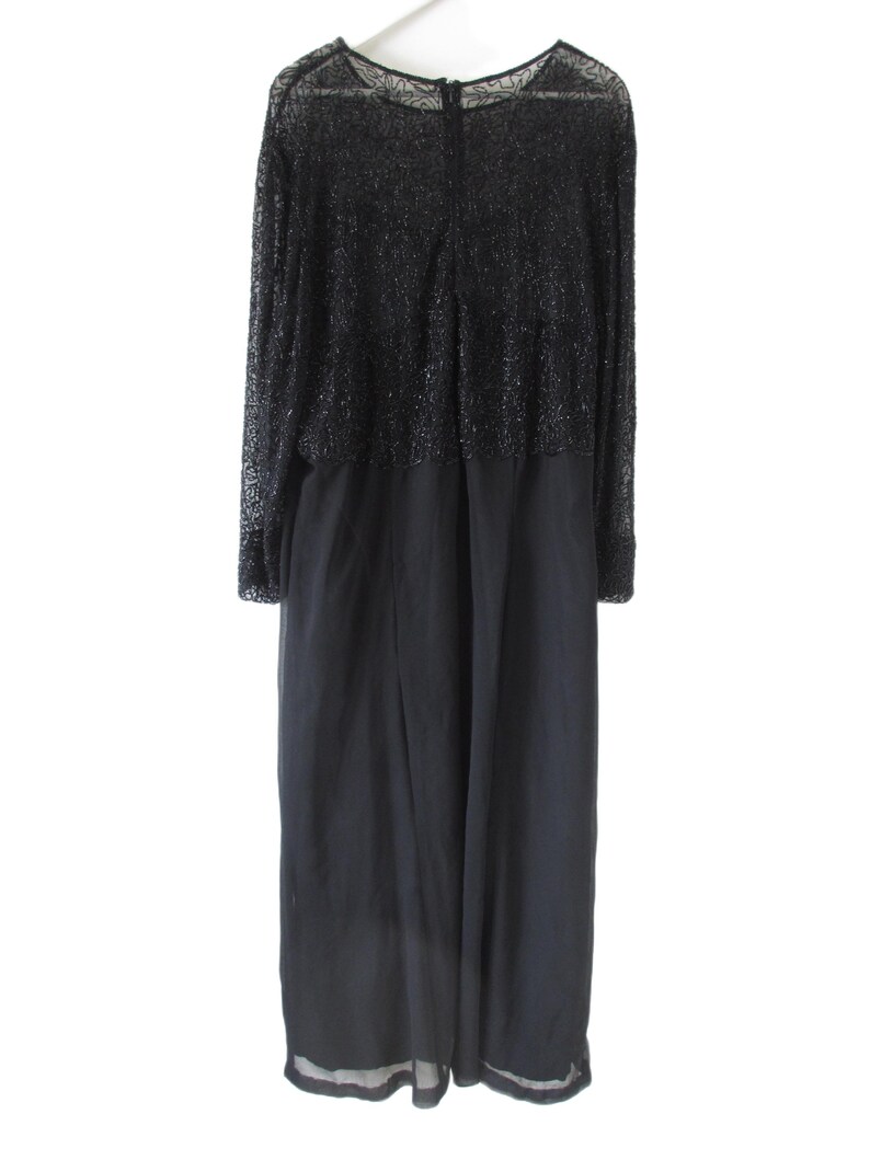 Puede incluir: Un vestido largo negro con corpi&ntilde;o de cuentas y mangas largas. El vestido tiene una falda fluida y cierre de cremallera en la espalda. La parte superior del vestido est&aacute; cubierta de peque&ntilde;as cuentas brillantes.
